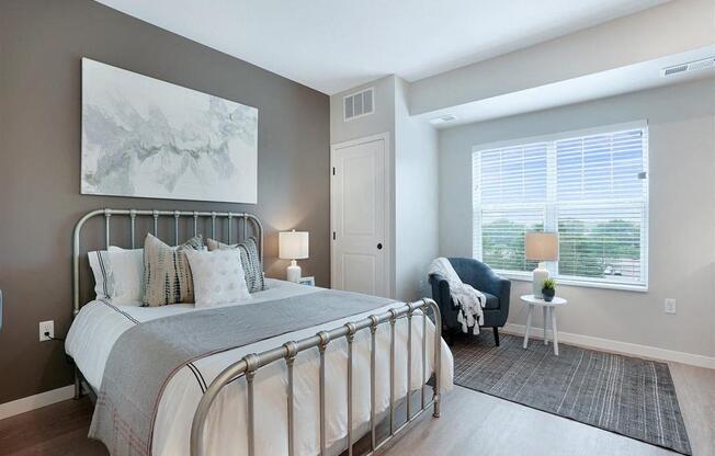 A bedroom with a large bed and a chair by the window.