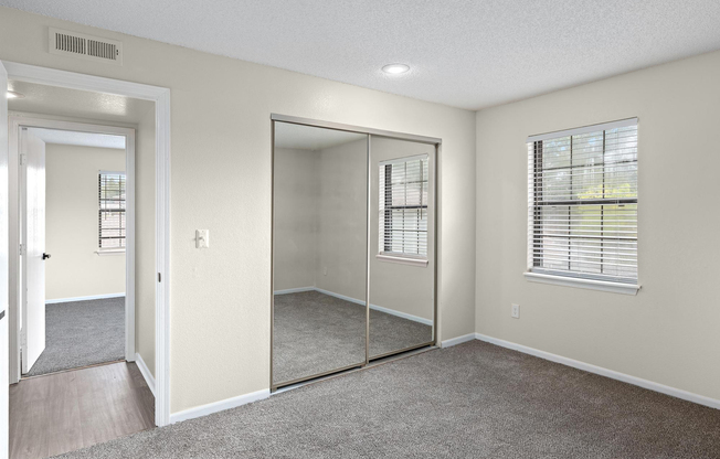 Gold carpeted bedroom interior and mirrored closet at The Arbor Apartments in Blue Springs, Missouri