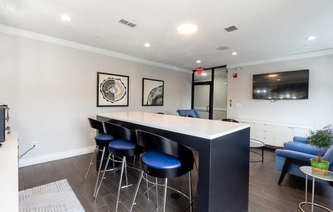 a bar with blue stools in a living room with a television