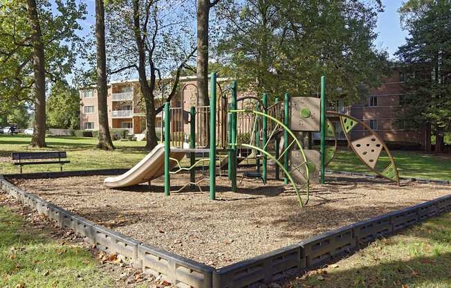 A playground with a slide, swings, and a seesaw.