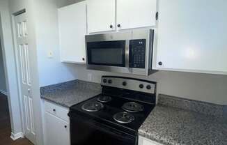 A kitchen with a stove top oven and microwave above it.