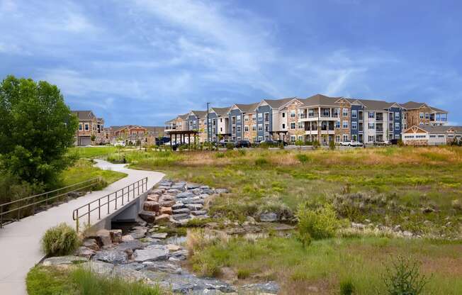 a bridge over a creek in front of an apartment building at Watermark on Twenty Mile, CO