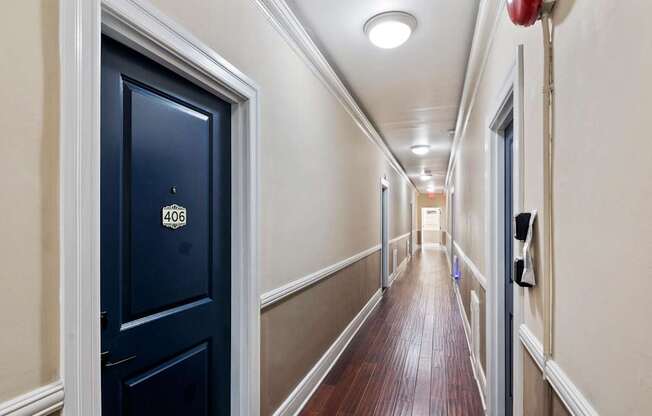 A hallway with a black door on the left and a red fire extinguisher on the right.