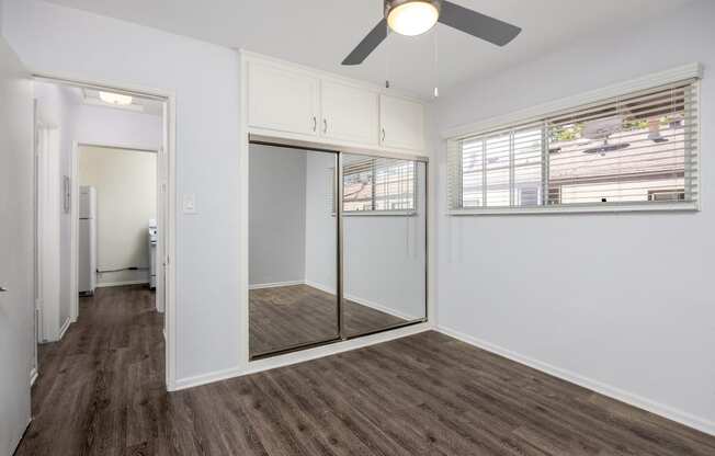 an empty room with a window and a ceiling fan