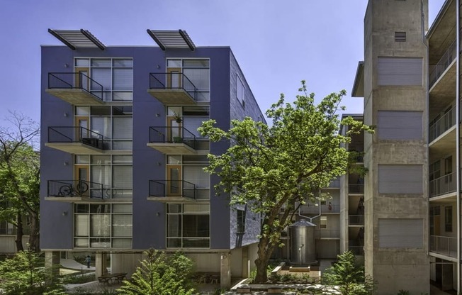 the exterior of an apartment building with trees and a courtyard