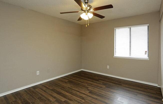 an empty room with a ceiling fan and wood floors