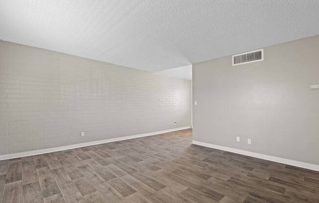 A room with wooden flooring and a wall-mounted air conditioner.