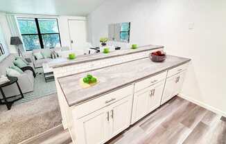 A kitchen with a large island and a dining table with chairs.