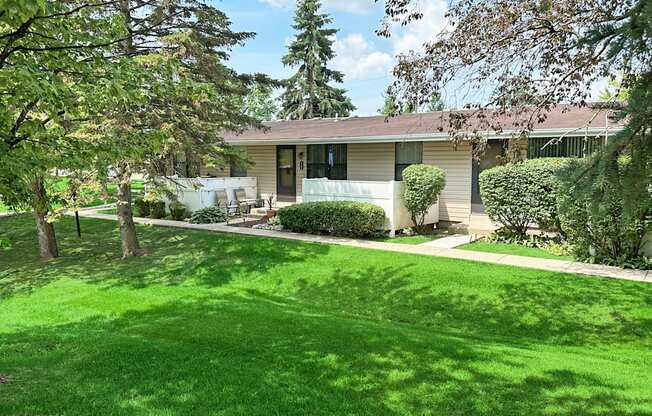 A house with a green lawn and trees in front.