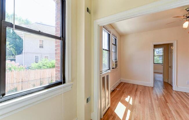 vacant living area with hardwood flooring and large windows at the klingle apartments in washignton dc