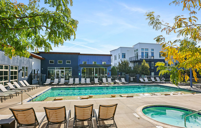 A pool surrounded by chairs and trees.