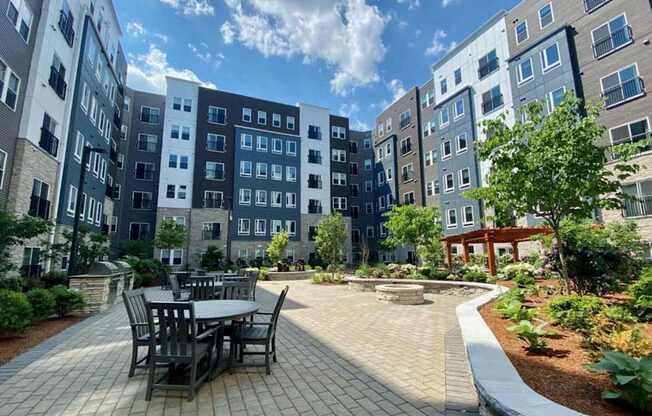 A beautifully landscaped courtyard featuring outdoor dining tables and lush greenery.
