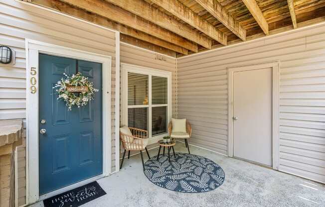 A blue door with a wreath on it and a sign that says "Welcome Home" on the mat.