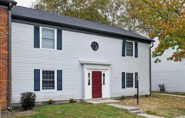 A house with a red door and a grey siding.