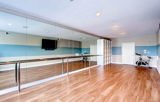 a workout room with mirrored walls and a wood floor