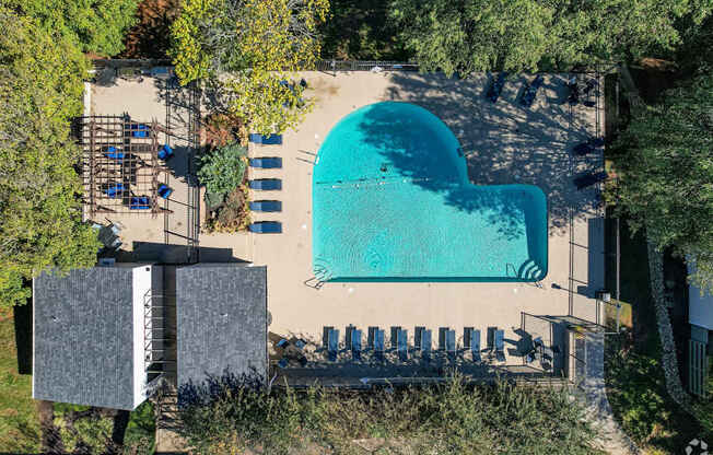 A heart-shaped pool surrounded by lounge chairs and trees.