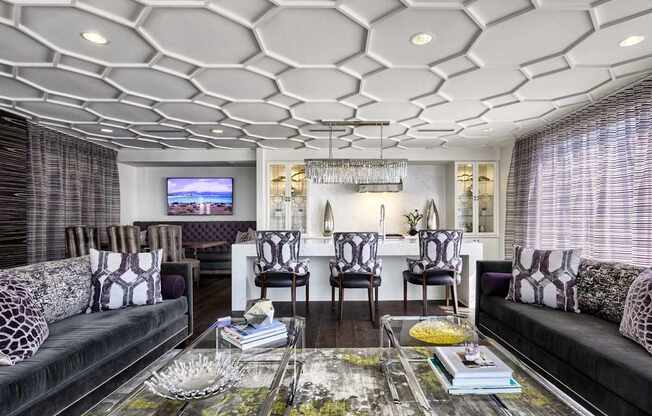A living room with a black couch and a glass coffee table.