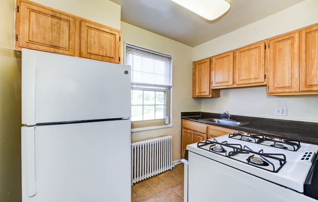 kitchen with wood cabinetry, tile flooring and window at the richman apartments in washington dc