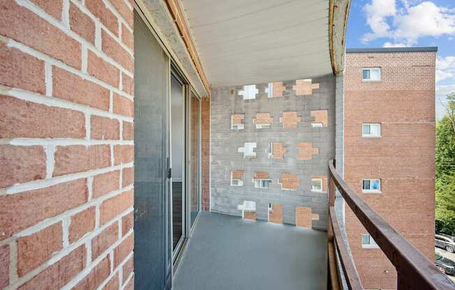 A balcony with a brick wall and a glass door.