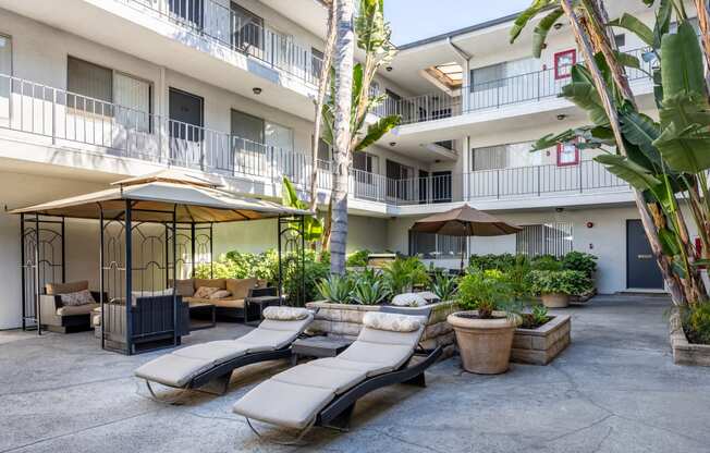 a courtyard with lounge chairs and umbrellas