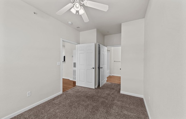 a spacious living room with carpet and a ceiling fan