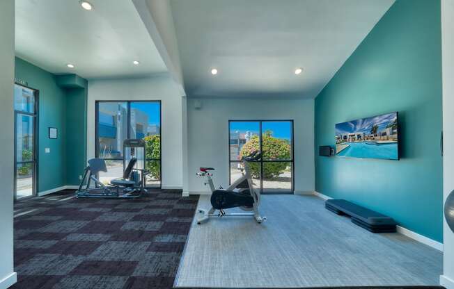 a workout room with blue walls and a view of the pool