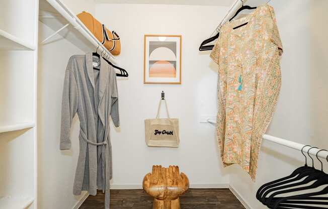 a closet with clothes hanging on the wall and a wooden chair