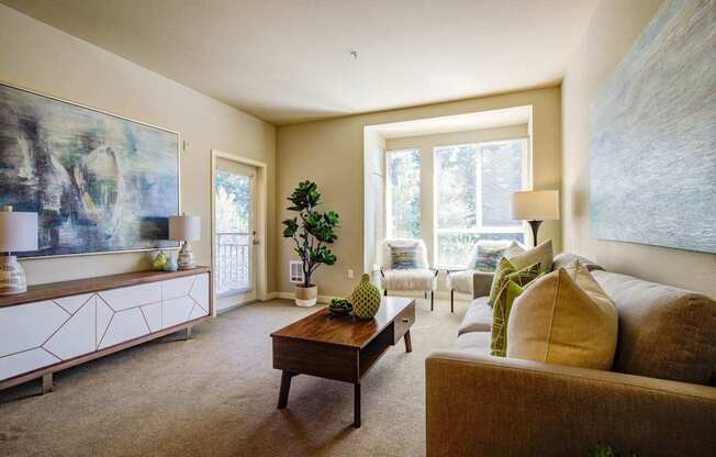 A living room with a brown couch, a wooden coffee table, and a painting on the wall.
