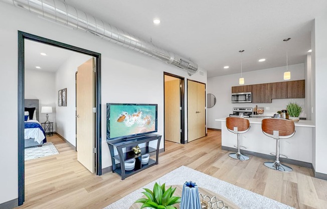 a living room with a tv and a kitchen with a bar