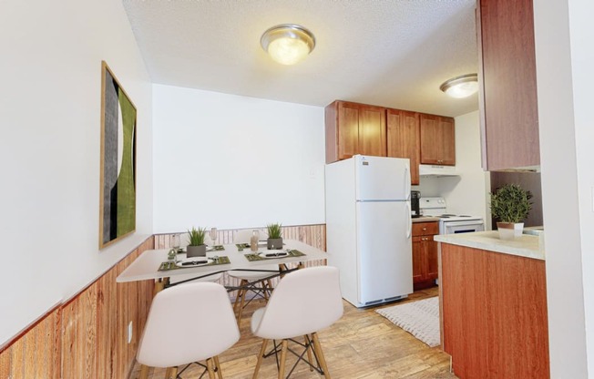 a dining area with a table and chairs and a kitchen in the background