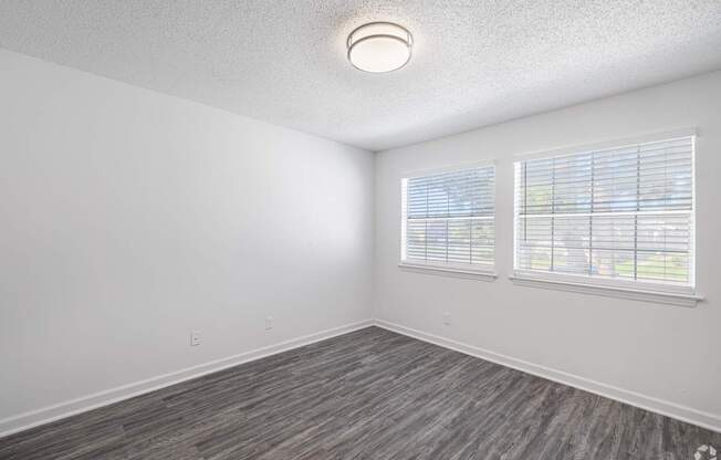 A room with a grey floor and a window with blinds.