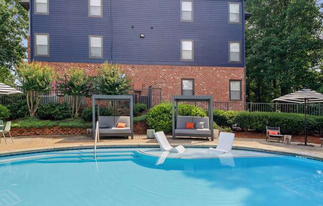 A blue swimming pool in front of a brick building.
