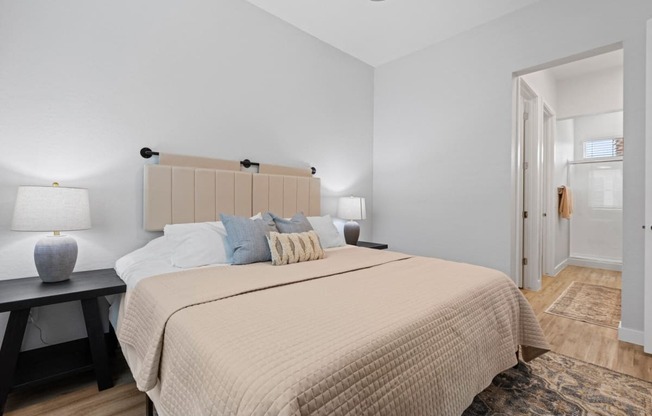 a bedroom with a large bed and a door to a bathroom at Village of Chandler Apartments, Chandler, 85249
