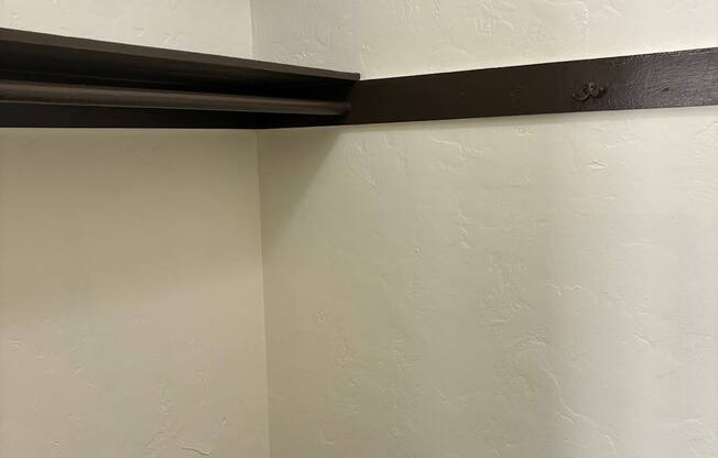 the corner of a room with white walls and a black shelf