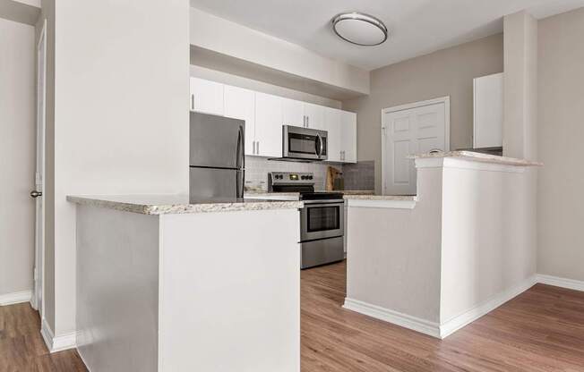 A kitchen with white cabinets and a marble island.