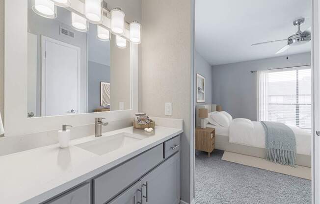 A bathroom with a vanity, a bed, and a ceiling fan.