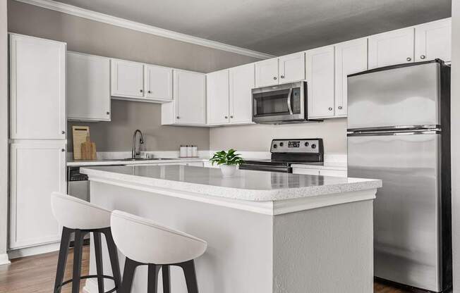 A modern kitchen with white cabinets and a white island.