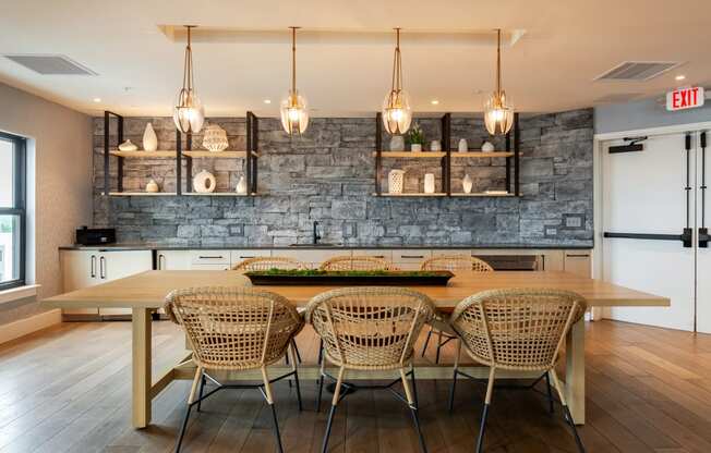 a dining area with a wooden table and chairs and a brick wall behind it  at Century West Pryor, Lee's Summit, Missouri