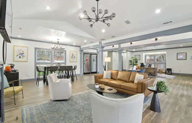 A living room with a brown couch and a chandelier.