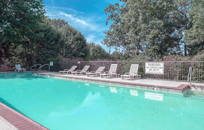 a swimming pool with chaise lounge chairs and trees