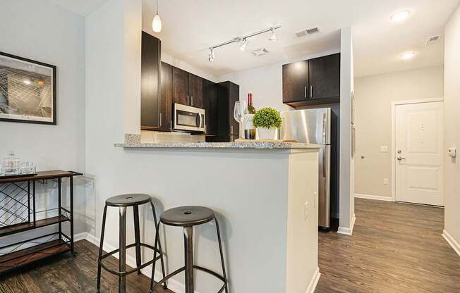 A kitchen with a white counter and black bar stools.