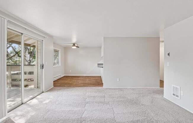 A spacious living room with a carpeted floor and a ceiling fan.