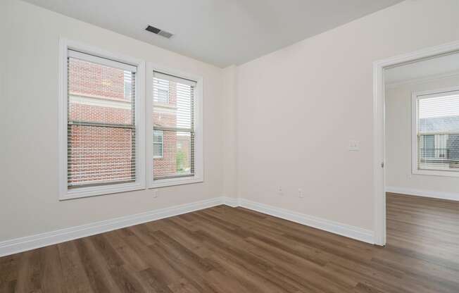 a bedroom with hardwood floors and two windows