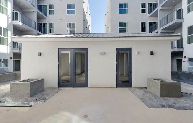 A white building with a black roof and two doors.
