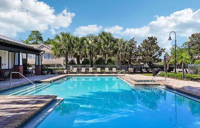 a swimming pool with palm trees and a house in the background