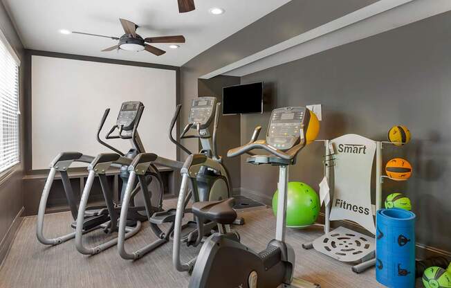 a gym with various exercise machines and a television