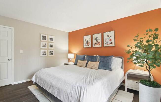 A bedroom with a bed, nightstand, and pictures on the wall.