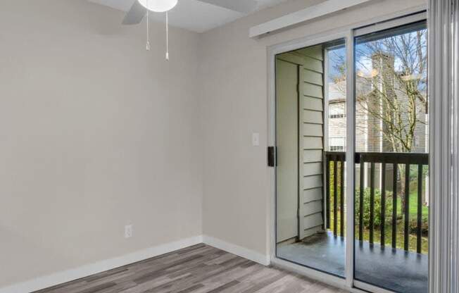 A room with a ceiling fan and sliding glass doors.