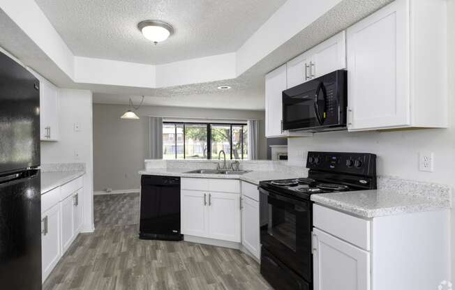 a kitchen with white cabinets and black appliances and a window