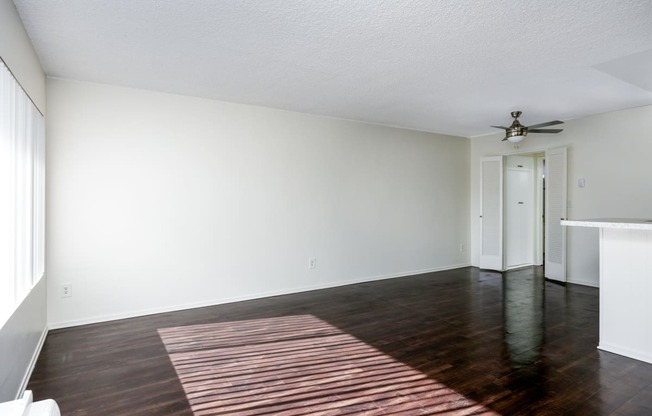 an empty living room with wood floors and a ceiling fan